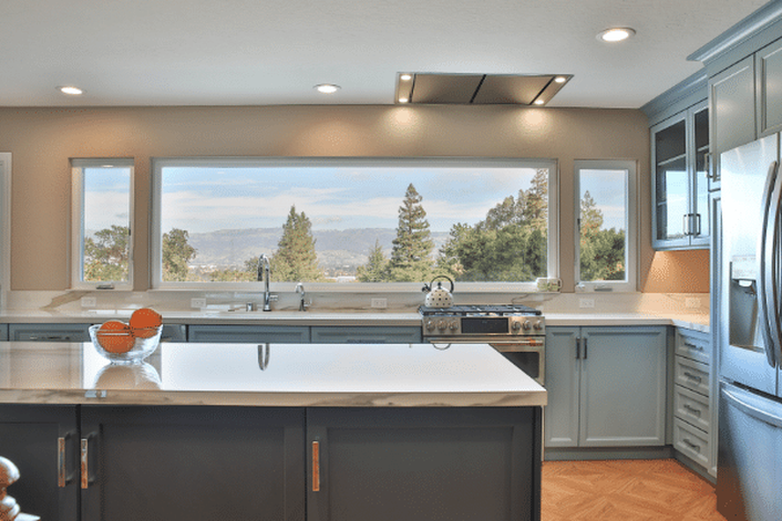 View of three-panel panoramic windows bove sink nd stove areas in this large kitchen design