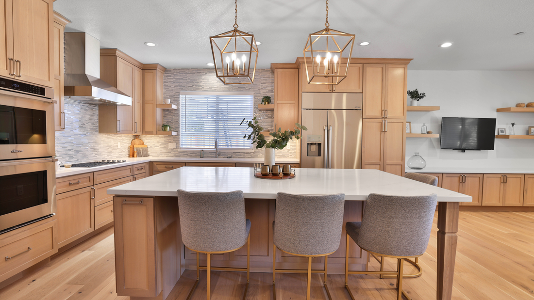 A large kitchen island stands in the foreground of this kitchen design featuring natural wood cabinets