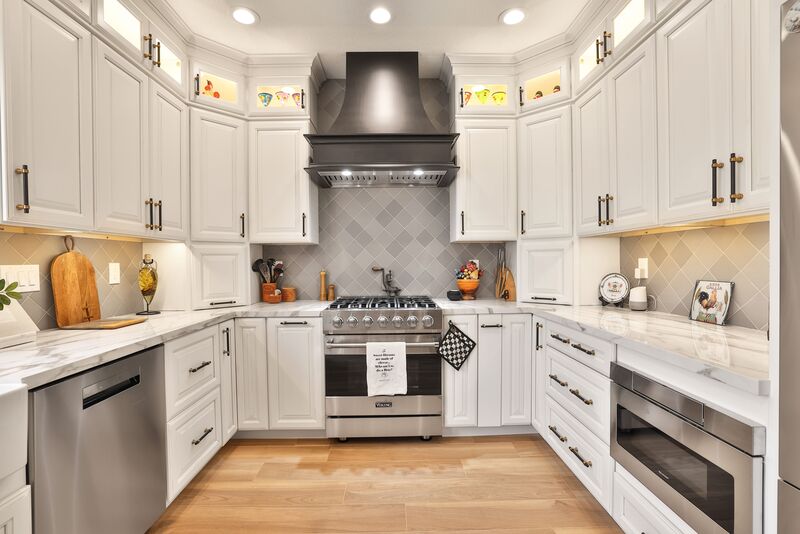 light wood floor kitchen with white cabinets and stainless steel appliances.