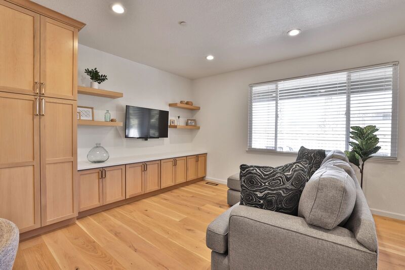 wood floor and cabinets. A grey couch with black pillows across from a TV.