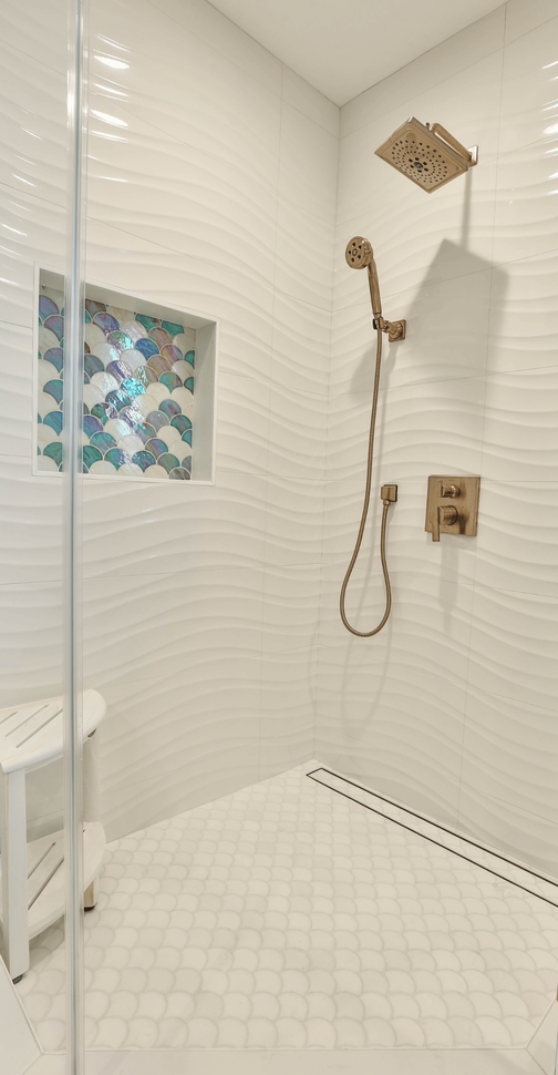 Tall image of shower stall with wavy textured field tiles and irradescent mermaid niche tiles
