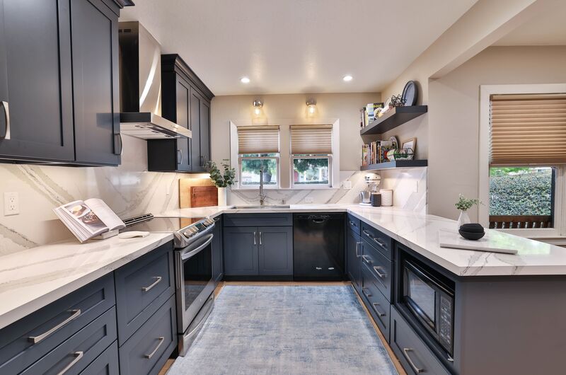 marble countertop with blue cabinets and double windows 