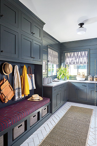 Laundry room with dark blue cabinets and white floor tile with hooks and a storage bench with cubbiies