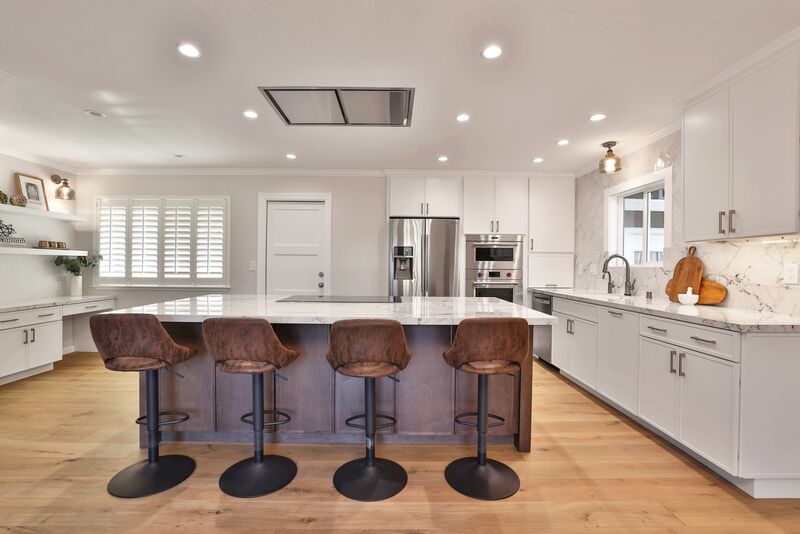 light wood floor with modern brown stools around an island with white countertops. 