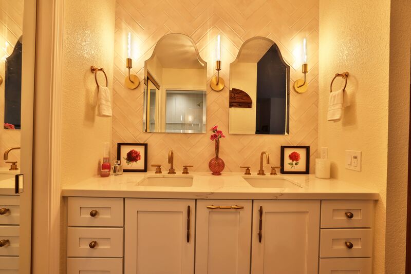 two half round mirrors with double sinks and a flower picture on each side of the white counter