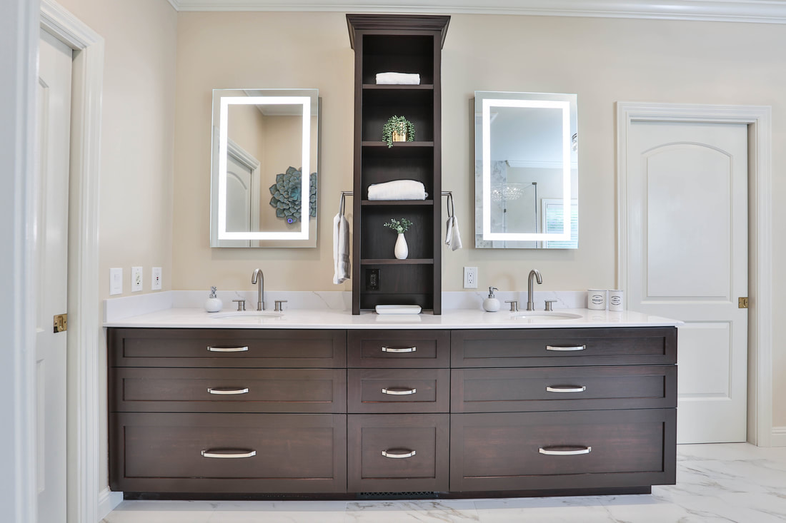 a transitional bathroom vanity with lighted mirrors and dark brown shaker-syle cabinets